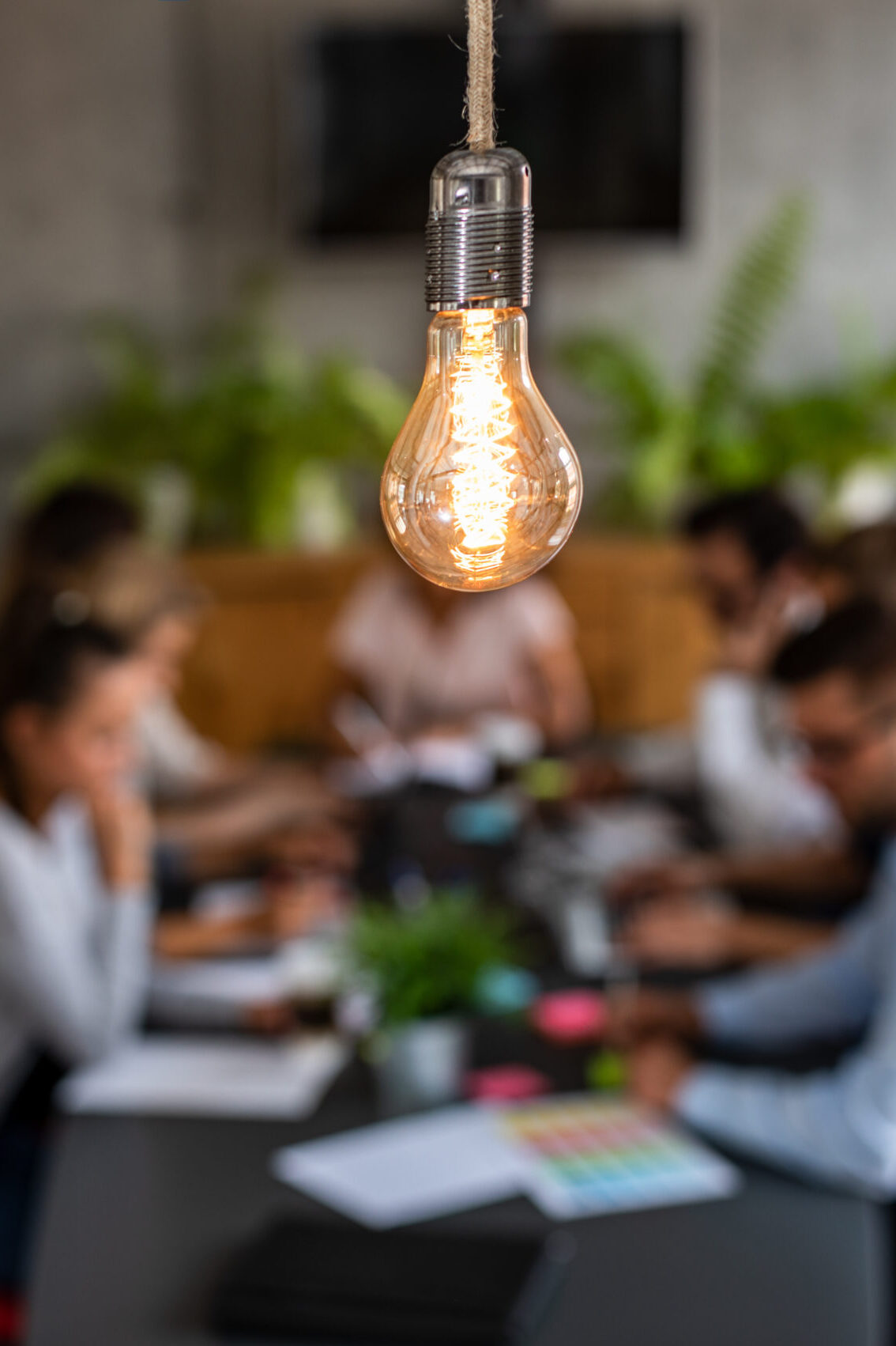 Primrose Watson diverse perspectives Business people sitting around a table in the background. A glowing light bulb as a new idea.
